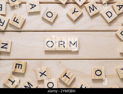 Tavola di legno con un mucchio di lettere di legno sparse intorno ad essa. Le lettere scrivono la parola ORM Foto Stock