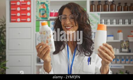 Farmacista donna sorridente che tiene i prodotti in una farmacia, mostrando l'esperienza di vendita al dettaglio nel settore sanitario. Foto Stock