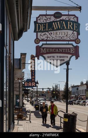 Guardando lungo il marciapiede, le persone che camminano e la strada del quartiere storico, con particolare attenzione alle indicazioni per il Delaware Hotel, Leadville, Colorado, Stati Uniti. Foto Stock