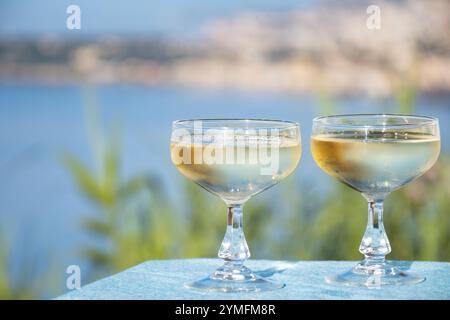 Spumante freddo, cava o champagne in due bicchieri da coupé sul tavolo con vista mare vicino a Mentone e Monte Carlo, Costa Azzurra, la Francia è estate Foto Stock