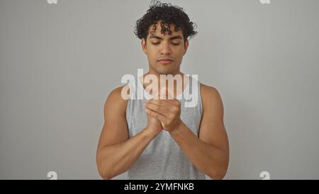 Bel giovane ispanico che applica crema sulle mani su sfondo bianco isolato Foto Stock