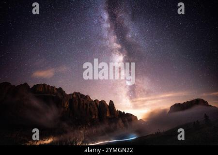 Uno splendido cielo notturno pieno di innumerevoli stelle, che illumina una maestosa montagna che si erge in primo piano in questa splendida scena Foto Stock