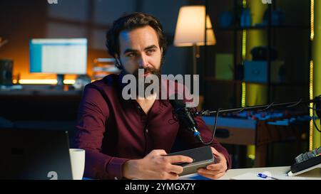 Allegra star di Internet che fa la revisione della tecnologia degli altoparlanti portatili Bluetooth per il canale delle piattaforme online, primo piano. Jolly influencer che presenta il dispositivo di riproduzione musicale al suo pubblico, la telecamera A. Foto Stock