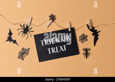 Cartello di trucco o dolcetto appeso a una stringa. Il segno è bianco e nero e ha un ragno sopra Foto Stock