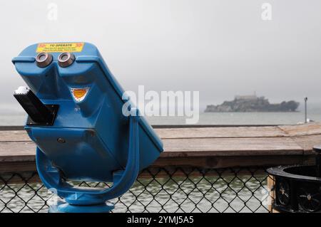 Telescopio blu che osserva la prigione di Alcatraz nella nebbiosa giornata di San Francisco Foto Stock