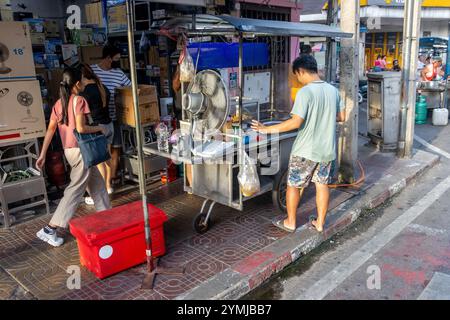 SAMUT PRAKAN, THAILANDIA, 16 GIUGNO 2024, il venditore sta preparando uno stand con fast food, sul marciapiede, nel tardo pomeriggio Foto Stock