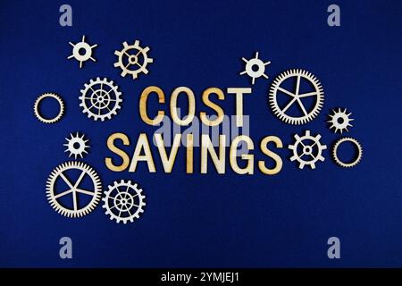 Risparmio sui costi lettere alfabetiche con elemento Gears su sfondo blu navy Foto Stock