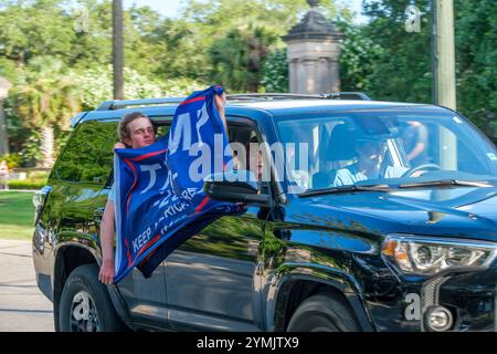 NEW ORLEANS, LOUISIANA. USA - 24 GIUGNO 2024: Giovani adolescenti con bandiera Trump manifestano da un veicolo in movimento fuori Audubon Place, una comunità recintata su St. Charles Avenue dove Trump sta organizzando un evento di raccolta fondi. Gli adolescenti stavano girando intorno al blocco e trollando i manifestanti anti trump. Il corteo di Trump non era ancora arrivato per la raccolta fondi. Foto Stock