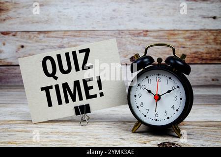 Testo dell'ora del quiz su carta con sveglia su sfondo in legno Foto Stock