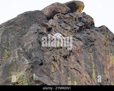 Avventuroso giovane alpinista maschile che sale sulla parete rocciosa di arenaria della Bastiglia nell'Eldorado Canyon State Park in Colorado. Foto Stock