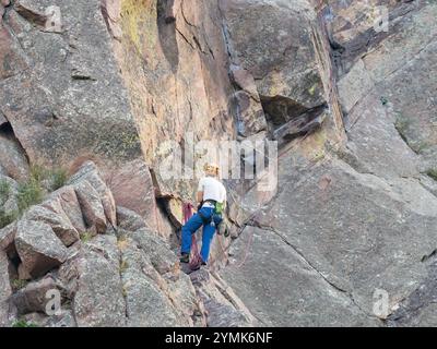 Un solo maschio arrampicatore in viaggio per un altro arrampicatore non raffigurato sulla Bastille Mountain nell'Eldorado Canyon State Park in Colorado. Foto Stock