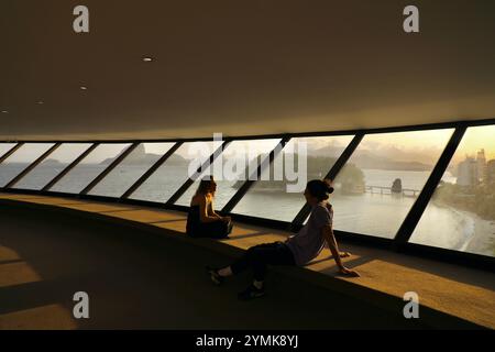 Due visitatori stanno chiacchierando al Museo di arte contemporanea Niterói di Niterói, Brasile. Inaugurato nel 1996, è stato progettato dall'architetto brasiliano Oscar Niemeyer. La sua struttura futuristica ricorda un disco volante. Oscar Niemeyer è uno degli architetti più famosi del Brasile. Appartiene al movimento di stile Internazionale. È noto soprattutto per aver costruito la capitale brasiliana Brasilia con l'urbanista Lúcio Costa, inaugurata nel 1960. Niteroi, attraverso la baia di Guanabara da Rio de Janeiro, è la seconda città al mondo con il maggior numero di edifici Niemeyer, dopo Brasilia. Foto Stock