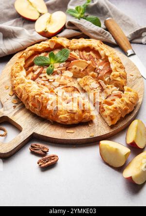 galette di mele appena sfornata, decorata con scaglie di mandorle e foglie di menta, servita su una tavola di legno Foto Stock