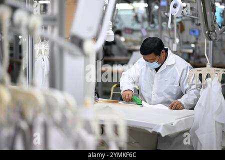 SUQIAN, CINA - 22 NOVEMBRE 2024 - Un lavoratore produce camicie su una linea di assemblaggio in un'officina di produzione intelligente in una fabbrica di abbigliamento a Suqian, Jiangs Foto Stock