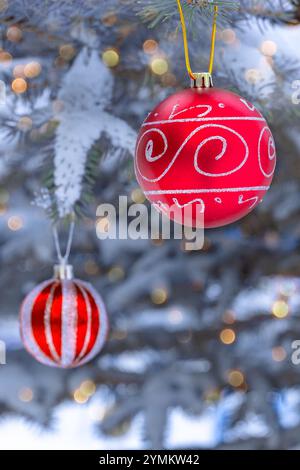 Palle di alberi di Natale luccicanti di colore rosso brillante sull'abete vivo nelle giornate invernali innevate e ghiacciate. Primo piano. Foto Stock