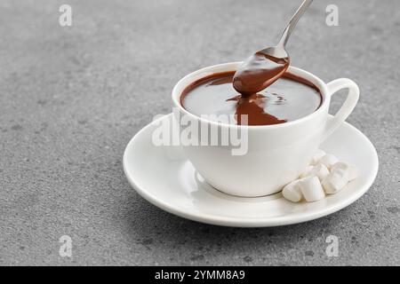 cioccolata calda con marshmallow in tazza e in cucchiaio sul tavolo Foto Stock