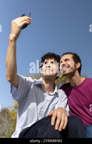 Due uomini che fanno un selfie in una giornata di sole, si godono il tempo insieme. Copia spazio Foto Stock