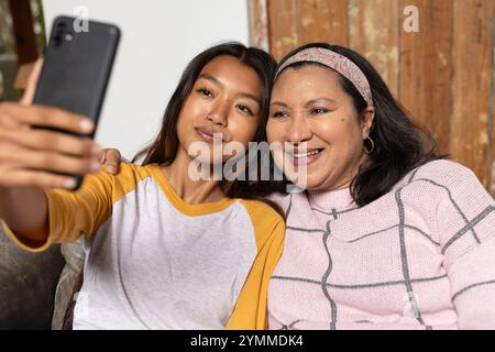 adolescente asiatica che scatta selfie con la nonna a casa, sorridendo e divertendosi insieme. Famiglia, legame, felicità, generazionale, tecnologia Foto Stock