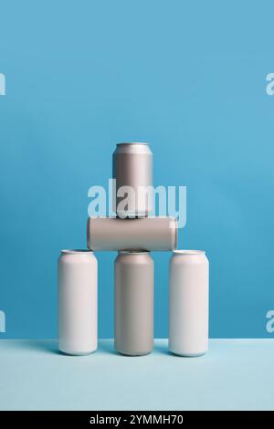 Tre eleganti barattoli in alluminio dal design minimalista, su sfondo blu in una composizione creativa. Mockup per birra, pubblicità di bevande analcoliche. Foto Stock