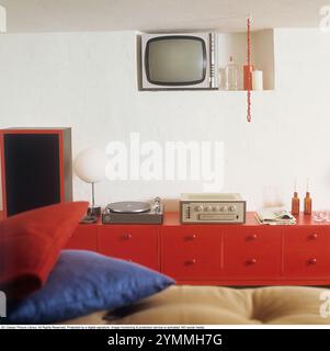 Interni della casa 1968. Una stanza nel seminterrato di una casa. Un impianto stereo con grammofono, amplificatore e altoparlante sul cabinet rosso. Una piccola tv sul muro. 1968 rif. DV23 Foto Stock