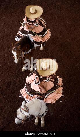 Gli Escaramuzas cavalcano i loro cavalli in una gara di rodeo a Chalco, città del Messico Foto Stock