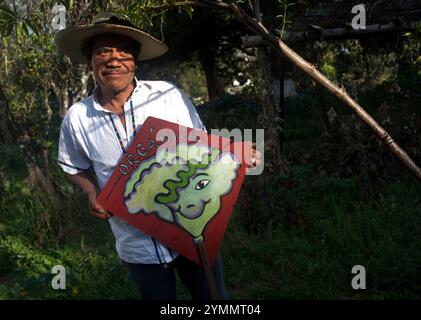 Tomas Villanueva Buendia 'Tomaicito' che lavora per proteggere e salvare le varietà originali del mais della sua nazione possiede un cartello con il dipinto Foto Stock