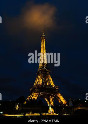 Parigi, Francia - 19 giugno 2024: La Torre Eiffel si erge maestosamente illuminata contro un cielo notturno buio, giustapposizione con le nuvole scintillanti sopra. Foto Stock
