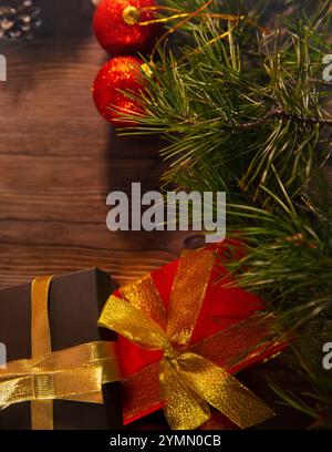 Striscione natalizio con molte confezioni regalo legate con nastri rossi e dorati e decorazioni sull'albero di Natale su sfondo in legno. Buon Natale Foto Stock
