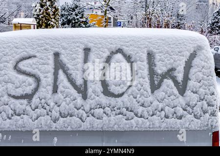 L'attacco dell'inverno, la prima nevicata, la parola neve scritta sul corpo dell'auto nella neve Foto Stock