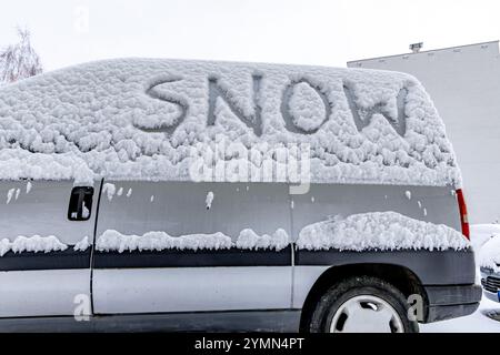 L'attacco dell'inverno, la prima nevicata, la parola neve scritta sul corpo dell'auto nella neve Foto Stock