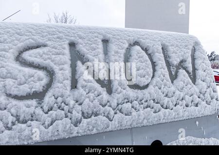 L'attacco dell'inverno, la prima nevicata, la parola neve scritta sul corpo dell'auto nella neve Foto Stock