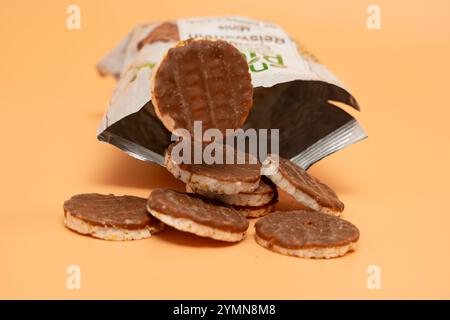 Aprire la confezione con cialde di riso al cioccolato su sfondo arancione. I wafer con gocce di cioccolato sono sparsi sul tavolo. Foto Stock