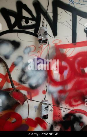 Yorkshire, Regno Unito : 31 maggio 2024 - due lattine di birra Carling appese tra i fili elettrici rotti di un edificio abbandonato coperto da graffiti Foto Stock