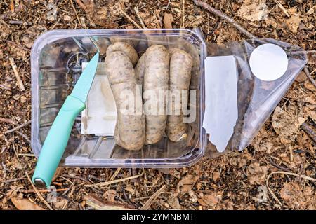 Salsicce crude in imballaggi in plastica e un coltello. Foto di alta qualità Foto Stock