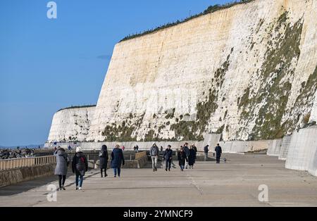 Brighton Regno Unito 22 novembre 2024 - gli escursionisti godono del sole e della brezza del tempo sulla passeggiata sotto la scogliera a Rottingdean vicino Brighton mentre Storm Bert si avvicina al Regno Unito: Credit Simon Dack / Alamy Live News Foto Stock