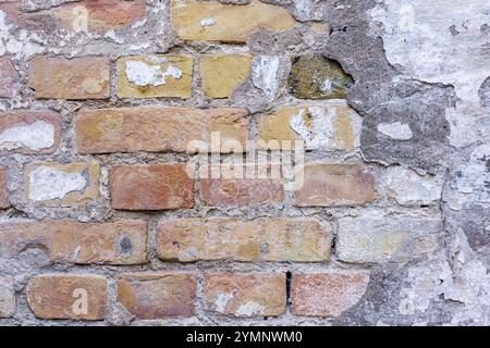 Posa di un vecchio muro di mattoni con resti di intonaco. Mattoni rossi e gialli. Foto Stock