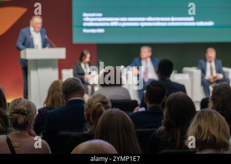 Conferenza d'affari con diversi relatori e un pubblico attento in un ambiente professionale. Foto Stock