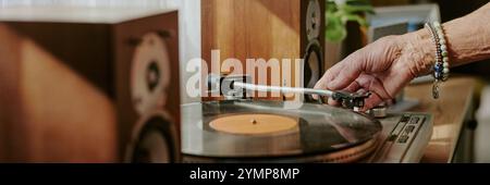 Primo piano della mano posizionando l'ago su un disco in vinile su un giradischi con altoparlanti sullo sfondo, vista dettagliata che evidenzia i componenti dei giradischi e gli altoparlanti Foto Stock