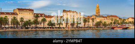 Tramonto sulla vivace passeggiata di Riva a Spalato, Croazia. Fiancheggiato da palme ed edifici storici, il lungomare è pieno di gente e colorfu Foto Stock