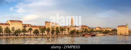 Tramonto sulla vivace passeggiata di Riva a Spalato, Croazia. Fiancheggiato da palme ed edifici storici, il lungomare è pieno di gente e colorfu Foto Stock