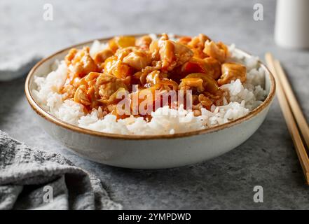 ciotola di riso bollito con salsa agrodolce di pollo sul tavolo da cucina grigio Foto Stock