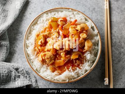 ciotola di riso bollito con salsa agrodolce di pollo sul tavolo da cucina grigio Foto Stock
