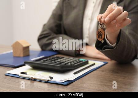 Agente immobiliare con chiave della casa e cancelleria al tavolo di legno, primo piano Foto Stock