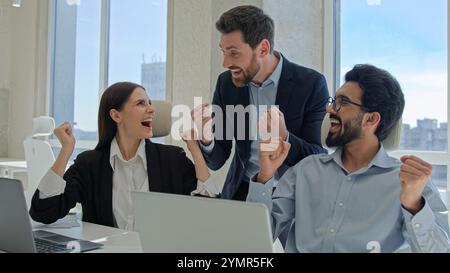 Un team creativo felice festeggia la vittoria in ufficio dati di vendita di successo sul mercato azionario uomini d'affari online e donne d'affari Foto Stock
