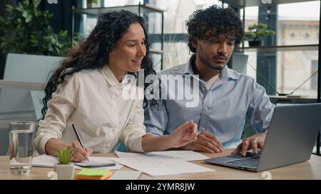 Agente di assicurazione datore di lavoro donna araba consultare il cliente maschio indiano discutere i dati di marketing di progetti aziendali sul laptop due multirazziale Foto Stock