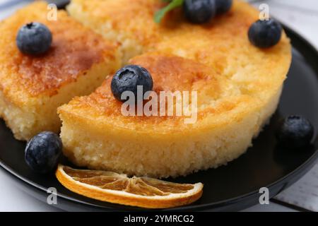 Deliziosa torta di semola con mirtilli e fette d'arancia su un tavolo di legno bianco, primo piano Foto Stock