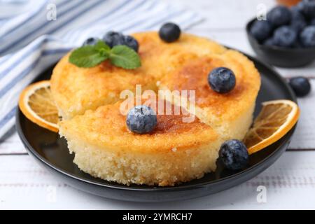 Deliziosa torta di semola con mirtilli e fette d'arancia su un tavolo di legno bianco, primo piano Foto Stock