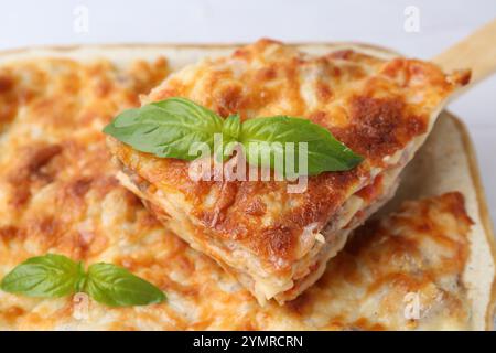 Deliziose lasagne cotte con basilico in piatto da forno sul tavolo, primo piano Foto Stock