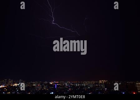 Lo skyline della città è illuminato da un fulmine luminoso che striscia attraverso il cielo scuro. La città sottostante è illuminata dalla luce del bullone, creato Foto Stock