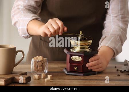 Donna che macina i chicchi di caffè sul tavolo in cucina Foto Stock